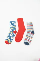 Pack de tres pares de medias de caña media con diseños diferentes: un par azul con flores blancas y amarillas, un par rojo liso y un par a rayas horizontales de colores.
