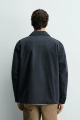 Parka de corte relajado confeccionada en mezcla de algodón color marrón. Presenta cuello solapa, cierre frontal con cremallera oculta y alamares metálicos, bolsillos de plastrón con solapa en la cadera y bolsillo de vivo en el pecho.