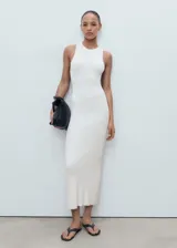 Vestido largo de punto color blanco, de corte entallado, con cuello halter y sin mangas.