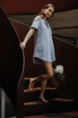 Camisa celeste de algodón con botones frontales, cuello clásico y mangas cortas con ribete negro.