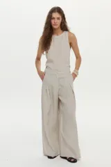 Pantalón de lino color beige, de pierna amplia, con elástico en la cintura, pinzas en el frente y bolsillos laterales y traseros.