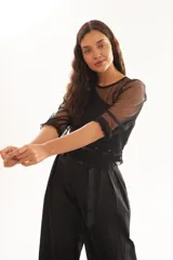 Blusa negra transparente de plumetí con frunces en los hombros y mangas 3/4.