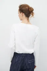 Remera de manga larga con cuello redondo, confeccionada en tejido de punto gris melange con costuras visibles en contraste.