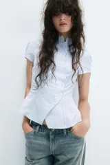 Camisa de manga corta con estampado de rayas verticales en tonos celeste y blanco, cuello alto y cierre frontal cruzado con botones.