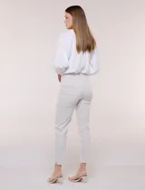 Pantalón color beige de corte entallado y largo cropped, confeccionado en tejido de punto con elasticidad técnica. Cuenta con pretina ancha y plana, bolsillos simulados al frente y bolsillos tipo ojal en la parte posterior.