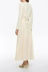 Falda midi color crema de corte línea A con vuelo, cremallera lateral invisible y pliegues irregulares cosidos en la cintura.