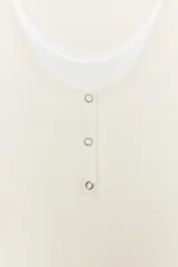 Camiseta efecto doble en color crudo y blanco, de manga corta y corte slim fit. Cuenta con escote redondo, cierre frontal parcial con botones a presión y diseño de capas superpuestas.