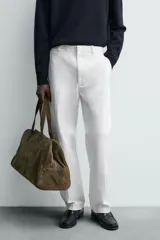 Pantalón chino de corte oversized confeccionado en tejido de algodón con estructura twill. Presenta bolsillos frontales, bolsillos traseros de vivo y cierre frontal con cremallera y gancho metálico oculto.
