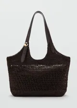 Bolso tipo tote color marrón con diseño de tejido calado de fibra natural, doble asa larga de hombro con detalle de hebilla ajustable y aplique metálico dorado, e incluye un bolso interno de tela con cierre de cremallera.