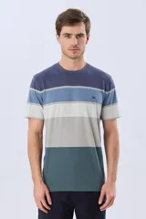 Remera de manga corta y cuello redondo, con diseño de bloques de color y franjas horizontales en tonos azul, celeste y gris, con pequeño logo bordado en el pecho.