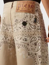 Bermuda de mezclilla color beige con estampado paisley en tonos marrón y blanco.