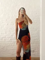 Vestido largo ajustado con un diseño de tirantes asimétricos y un estampado floral multicolor sobre fondo negro, con un tajo lateral en la pierna.