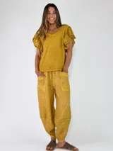 Pantalón de lino color amarillo mostaza, de corte bombacho y relajado, con bolsillos delanteros aplicados y cintura elástica.