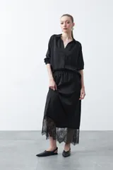 Falda midi negra de caída fluida con cintura elastizada y un amplio detalle de encaje negro en el bajo.