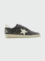 Zapatillas Golden Goose modelo Ballstar Nabuk, confeccionadas en gamuza y cuero color gris oscuro, con la característica estrella blanca en el lateral, suela con efecto desgastado y detalles de inscripción dorada.