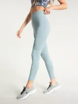 Calza deportiva de tiro alto con largo hasta el tobillo, confeccionada en tejido técnico elástico de color celeste. Presenta un diseño minimalista sin bolsillos y un pequeño logo bordado en la cadera.