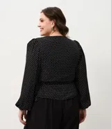 Blusa de crepé con estampado de lunares, diseño cruzado con escote en V, mangas largas con puños elásticos y lazo lateral ajustable. Incluye forro interno.