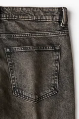 Jean de corte recto y calce regular, confeccionado en denim de algodón con efecto lavado desgastado en tono gris oscuro. Presenta diseño clásico de cinco bolsillos, cierre frontal con botón y costuras reforzadas.