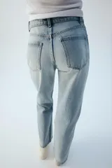 Jeans wide leg de tiro alto y cinco bolsillos, confeccionados en denim con lavado azul medio y efecto desgastado. Presenta cierre frontal con cremallera y botón metálico.