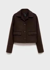 Chaqueta de corte recto confeccionada en mezcla de lana, con cuello camisero, cierre frontal de botones y dos bolsillos de solapa en el frente.