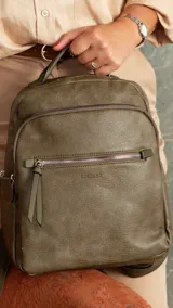 Mochila urbana color beige de símil cuero, con dos bolsillos frontales, bolsillo principal de gran capacidad con dos bolsillos internos con cierre y uno abierto, bolsillos laterales abiertos, asa de mano y correas regulables en galón.