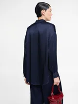 Camisa de corte amplio y silueta clásica, confeccionada en un tejido con textura arrugada sutil que aporta un acabado elegante y sofisticado. Presenta cuello camisero, cierre frontal con botones y mangas largas con puños abotonados.