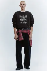 Buzo negro de cuello redondo con estampa frontal inspirada en la banda Ramones, hombros caídos y corte holgado.