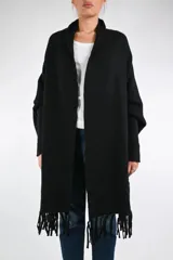 Ruana de punto color negro con flecos en el ruedo y mangas largas ajustadas con acabado acanalado. Presenta un diseño envolvente y abierto sin botones.