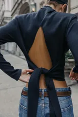 Jersey de punto de cuello subido y manga larga con hombreras. Presenta un diseño de espalda abierta con detalle de nudo.