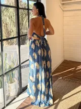 Vestido largo con estampado de hojas en tonos verde y blanco, con escote halter y espalda descubierta.