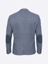 Saco de paño marrón con diseño a cuadros en tonos marrón, rojo y blanco. Tiene cuello con solapas, bolsillos de plastrón en pecho y cadera, mangas con coderas en contraste de color, forro estampado y aberturas en espalda.