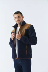 Campera de sherpa para hombre, color azul marino con detalles en marrón. Tiene cuello alto, cierre frontal y bolsillos laterales con cierre.