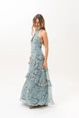 Vestido largo celeste con estampado abstracto en tonos marrones, escote halter con abertura en el frente y volados escalonados en la falda.