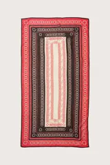 Pareo largo de diseño rectangular con estampado geométrico de cadenas en tonos rojo, negro y crema. Presenta un marco decorativo con bordes en contraste y un panel central claro.