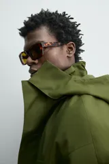 Parka técnica color verde militar de corte relaxed fit con cuello subido y capucha desmontable. Cuenta con bolsillos con solapa en el pecho y en la cadera, cintura ajustable con cordón y cierre frontal de cremallera oculta por solapa con botones a presión. Incluye un chaleco interior desmontable acolchado.