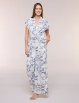 Enterito largo color blanco con estampa ilustrada en azul estilo Toile de Jouy, escote en V cruzado, mangas cortas caídas, bolsillos laterales, pantalón amplio wide leg y cinturón incorporado con hebilla metálica.