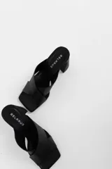 Sandalias de tacón color beige, con tiras cruzadas en el empeine y tacón geométrico negro.