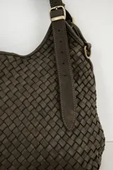 Cartera tipo hobo color suela, confeccionada en cuero con diseño trenzado y correa ajustable con hebilla metálica dorada.
