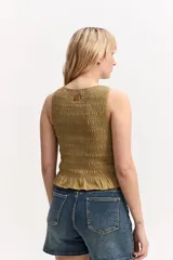 Top verde militar con textura fruncida de nido de abejas, cuello halter y detalle de volado en el ruedo.