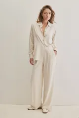 Pantalón negro de pierna ancha y calce fluido, con pinzas delanteras y bolsillos laterales.