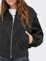 Campera de efecto cuero con cierre frontal, cuello camisero, mangas largas abullonadas con puños acanalados y diseño de paneles verticales.