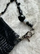 Mini cartera de cuero con textura simil cocodrilo, color marrón, con manija corta decorada con cuentas de colores y herrajes metálicos.