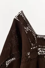 Vestido corto de algodón color marrón, con escote redondo y mangas tres cuartos. Presenta detalles de bordados a tono y aplicaciones de tejido perforado calado en toda la prenda.