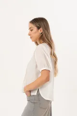 Blusa blanca de mangas cortas con cuello redondo y abotonadura frontal.