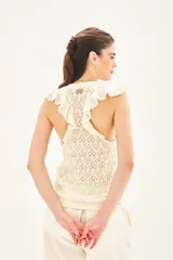 Musculosa de punto calado color crudo, con volados en las sisas y cuello redondo.