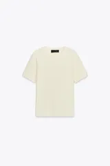 Jersey de manga corta color crema, con cuello redondo y tejido de punto suave.