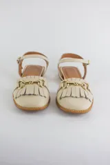 Sandalias de cuero color celeste, con punta cerrada, flecos frontales y detalle de estribo metálico dorado. Tienen tira ajustable al tobillo y suela plana con pequeño taco.