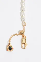 Pulsera dorada con perlas de resina y finas cadenas colgantes, con cierre de mosquetón ajustable y dije de corazón esmaltado.