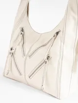 Cartera hobo negra de cuero sintético con costuras blancas decorativas y múltiples cierres diagonales en el frente. Tiene una correa de hombro ajustable.