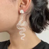 Par de aros colgantes con forma de serpiente plateada con detalles en negro.